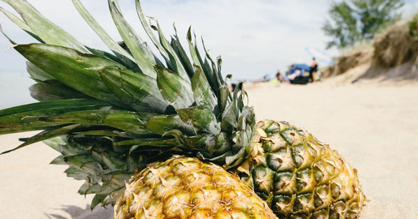 Close-up of ripe pineapples on a sunny beach, embodying tropical vibes and natural freshness.