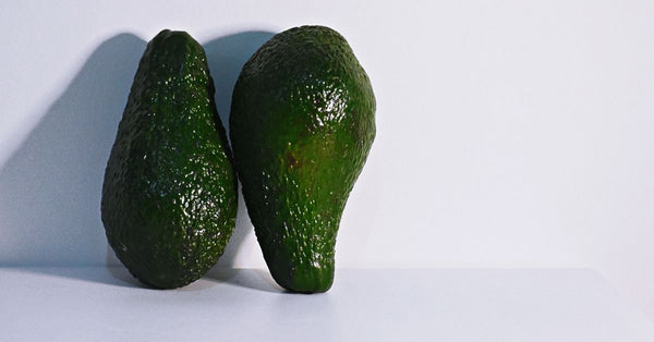 Two fresh avocados on a clean white background, highlighting healthy nutrition.