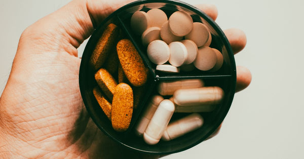 Close-up of a hand holding different types of supplements and vitamins.