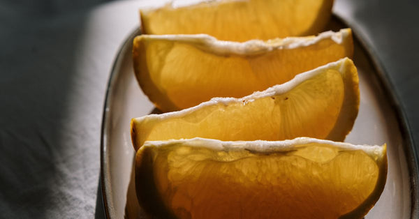 Close-up of juicy orange slices on a ceramic plate in natural light.
