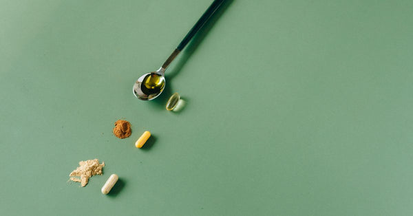 Assorted herbal supplements and powders on a green backdrop with a spoon.
