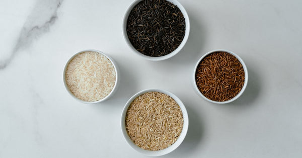 Four bowls showcasing different rice varieties on a marble surface, flatlay style.